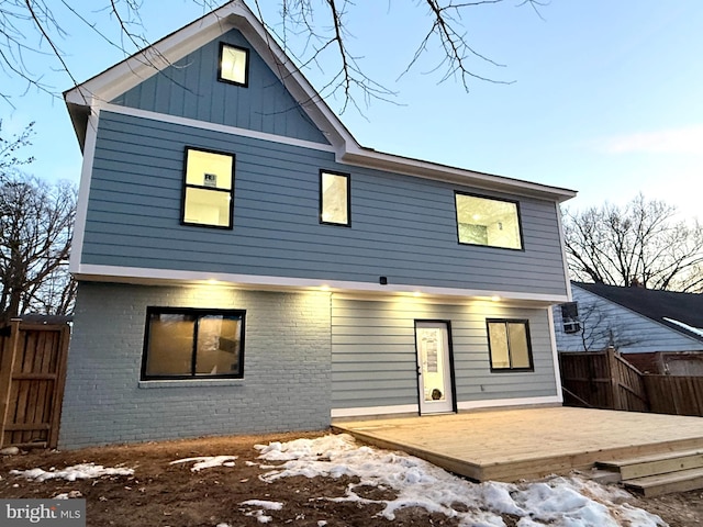 rear view of house featuring a deck, brick siding, and board and batten siding