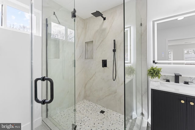full bath featuring a marble finish shower and vanity