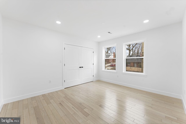 empty room featuring recessed lighting, light wood-type flooring, and baseboards
