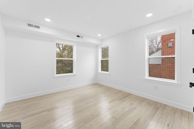 spare room featuring light wood-style flooring, visible vents, and baseboards