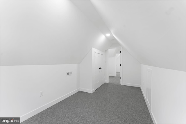 bonus room featuring lofted ceiling, visible vents, baseboards, and dark colored carpet