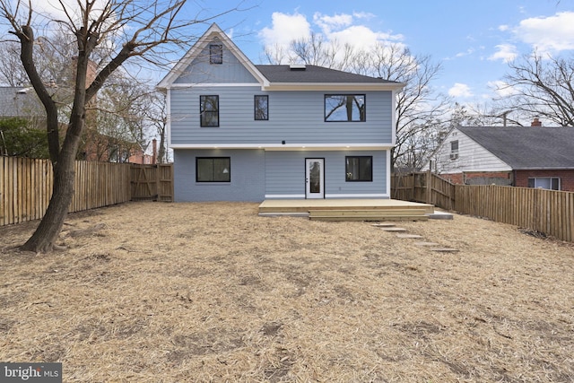 rear view of property featuring brick siding, a fenced backyard, and a wooden deck
