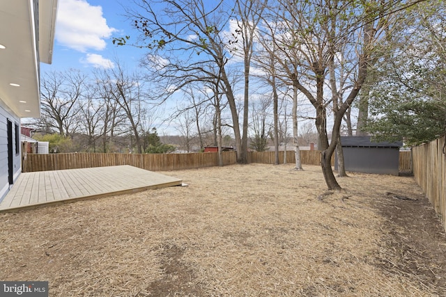 view of yard with a storage shed, an outbuilding, a fenced backyard, and a wooden deck