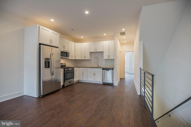 kitchen with appliances with stainless steel finishes, sink, white cabinets, and backsplash