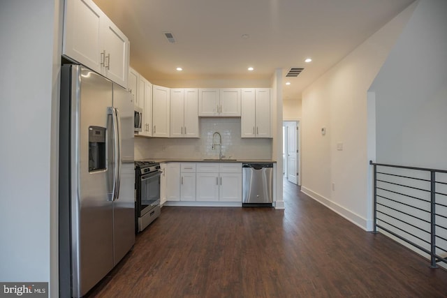 kitchen with white cabinetry, sink, dark hardwood / wood-style flooring, decorative backsplash, and stainless steel appliances