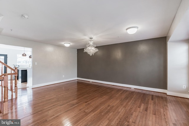 spare room with hardwood / wood-style floors and a notable chandelier