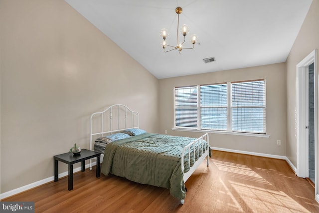 bedroom with an inviting chandelier, lofted ceiling, and light wood-type flooring