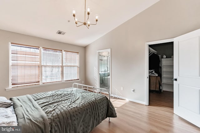 bedroom featuring lofted ceiling, an inviting chandelier, light hardwood / wood-style floors, a walk in closet, and a closet