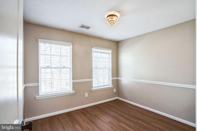 empty room with a healthy amount of sunlight and dark hardwood / wood-style floors