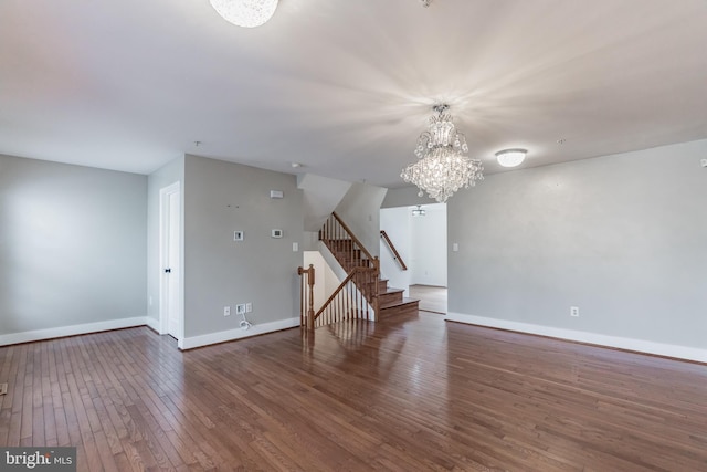 empty room featuring an inviting chandelier and dark hardwood / wood-style flooring