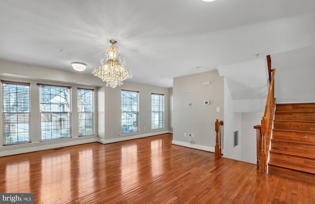 unfurnished living room with a chandelier and light hardwood / wood-style floors