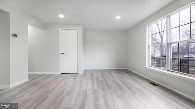 spare room featuring a textured ceiling and light wood-type flooring