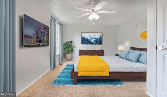 bedroom with ceiling fan, light colored carpet, and a textured ceiling