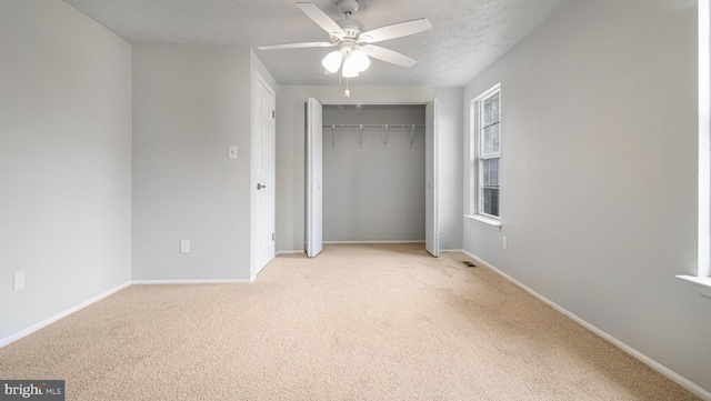 unfurnished bedroom with ceiling fan, light colored carpet, a closet, and a textured ceiling