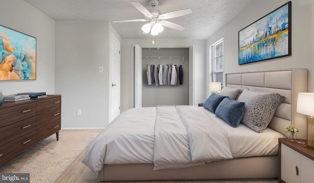 bedroom with light carpet, ceiling fan, a closet, and a textured ceiling