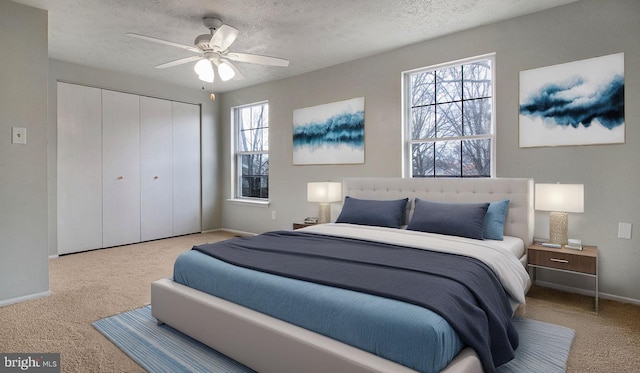 carpeted bedroom featuring ceiling fan, a closet, and a textured ceiling