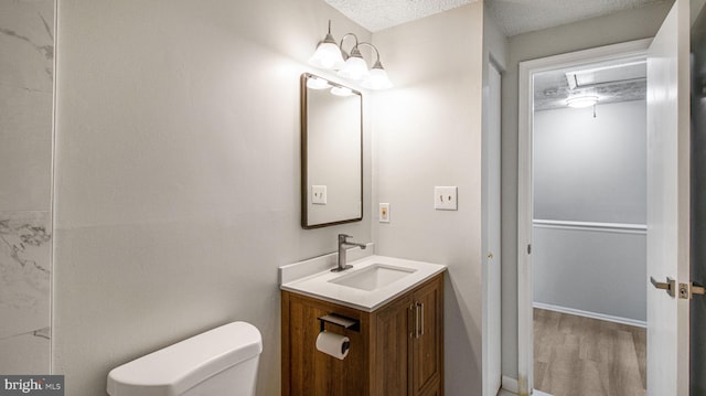 bathroom featuring hardwood / wood-style flooring, vanity, a textured ceiling, and toilet