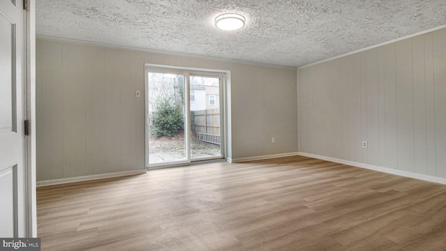 empty room with ornamental molding, a textured ceiling, and light hardwood / wood-style floors