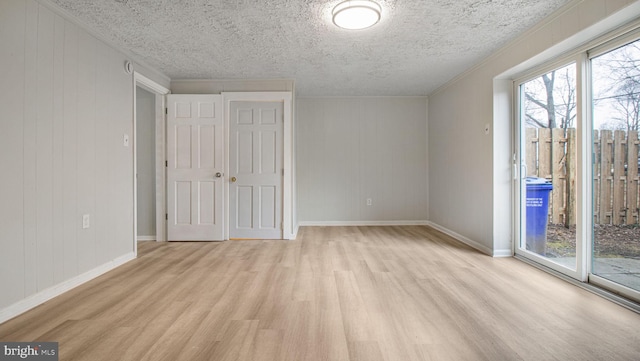 unfurnished room featuring crown molding, light hardwood / wood-style flooring, and a textured ceiling