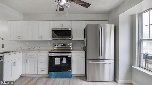 kitchen featuring white cabinetry, stainless steel appliances, and a wealth of natural light