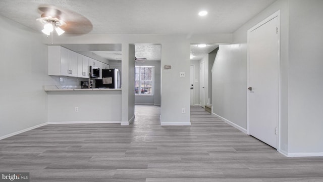 kitchen with ceiling fan, light wood-type flooring, white cabinets, and appliances with stainless steel finishes