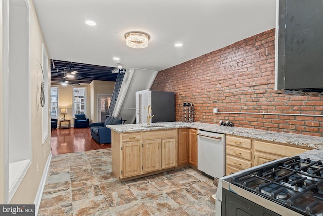 kitchen with stainless steel range with gas cooktop, kitchen peninsula, dishwasher, and light brown cabinets