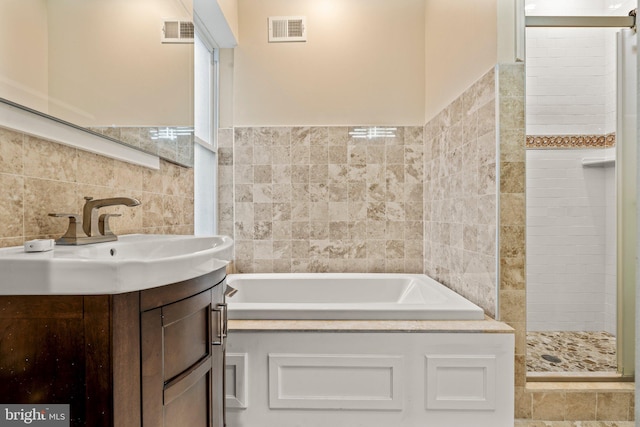 bathroom with vanity, independent shower and bath, and tile walls