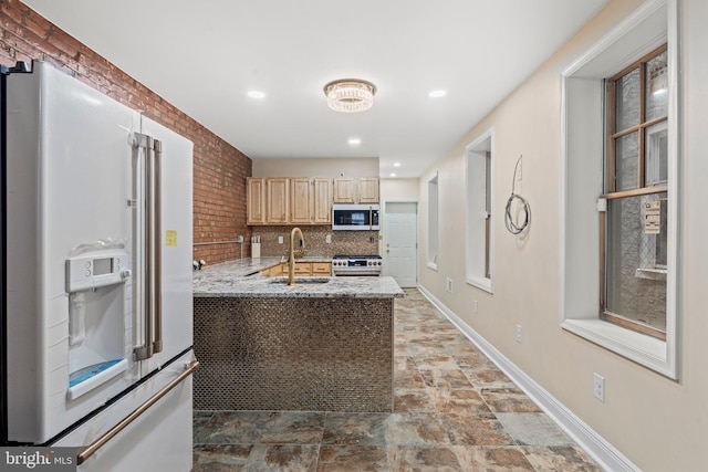 kitchen featuring sink, backsplash, high end appliances, light stone counters, and light brown cabinets