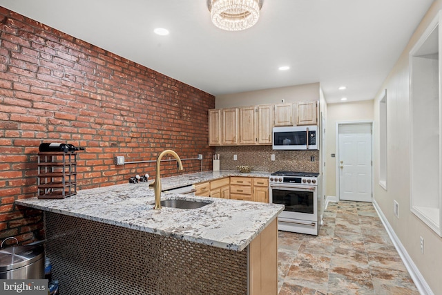 kitchen with sink, kitchen peninsula, light stone countertops, light brown cabinets, and gas range oven