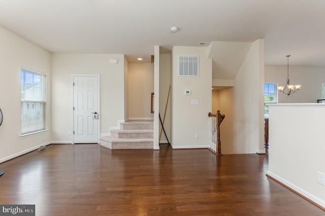 spare room with a healthy amount of sunlight, dark hardwood / wood-style floors, and a notable chandelier