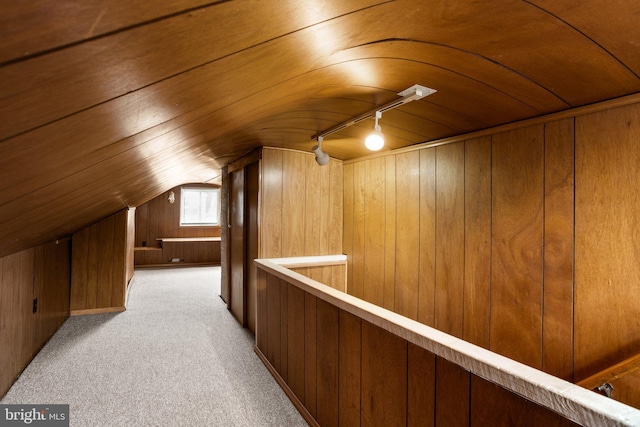 bonus room with vaulted ceiling, light carpet, and wood walls