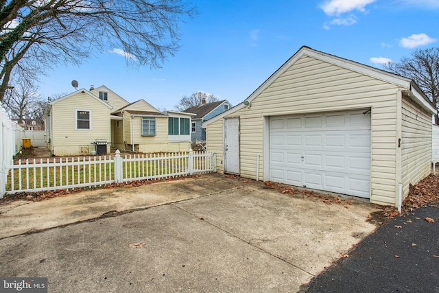 view of front of home with a garage, driveway, an outdoor structure, and fence private yard