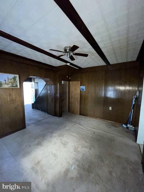 interior space featuring lofted ceiling with beams, concrete floors, and wood walls