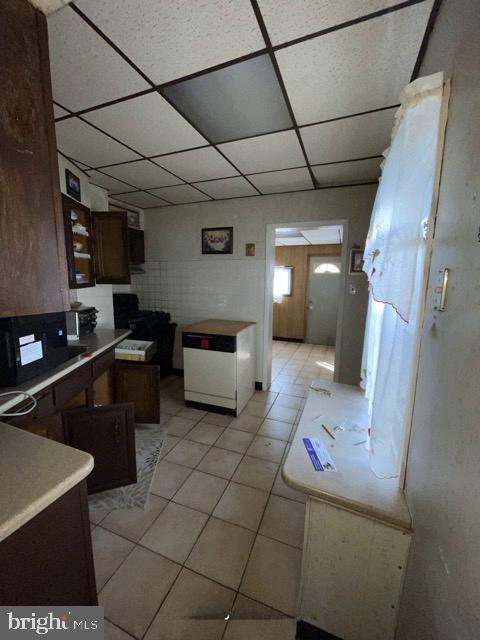 kitchen featuring a drop ceiling, dark brown cabinetry, and light tile patterned flooring