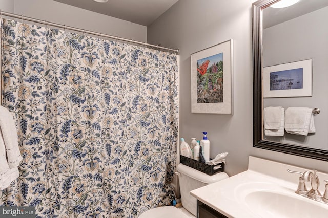 bathroom with walk in shower, vanity, and toilet