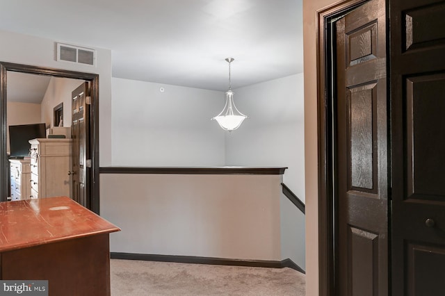 kitchen featuring light carpet, pendant lighting, and dark brown cabinetry