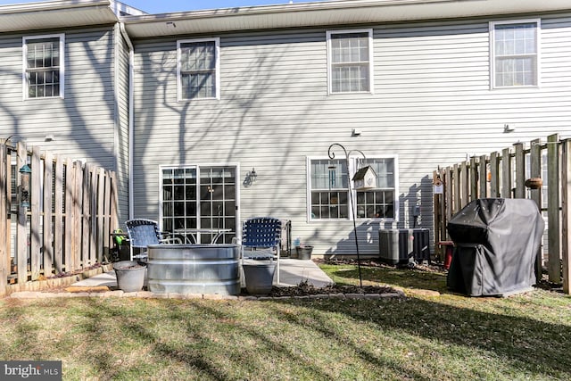 back of property featuring a lawn and central air condition unit