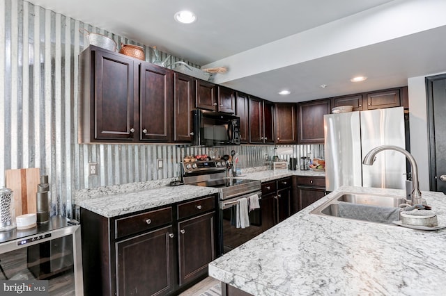 kitchen with appliances with stainless steel finishes, sink, wine cooler, light stone countertops, and dark brown cabinets