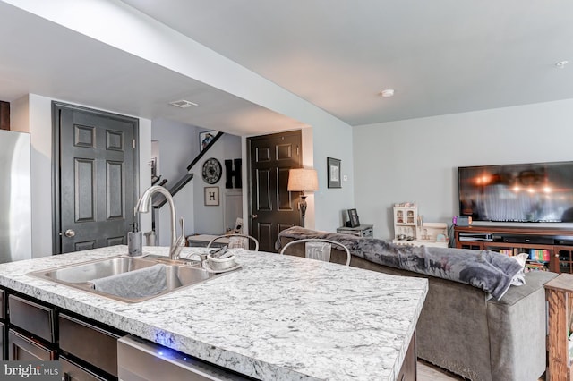 kitchen featuring sink, dishwasher, and an island with sink