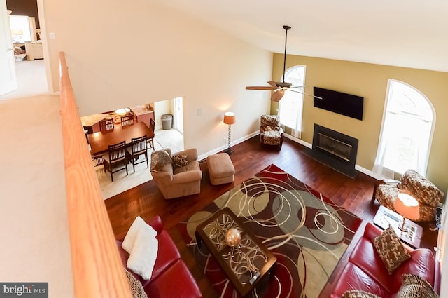 living room with ceiling fan, dark hardwood / wood-style flooring, and vaulted ceiling