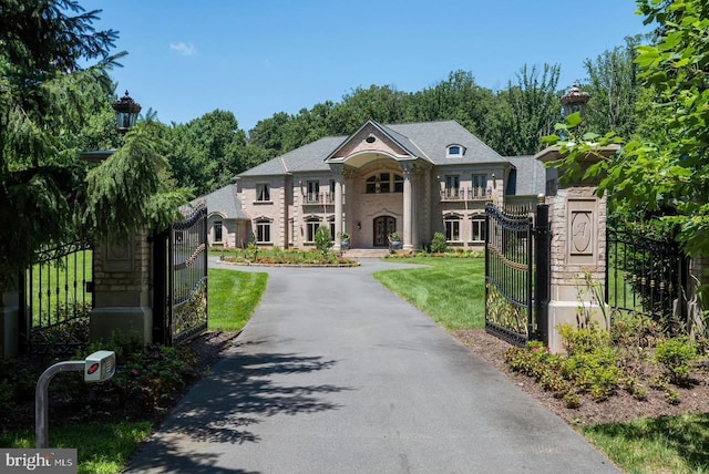 greek revival inspired property with driveway, a gate, fence, and a front yard