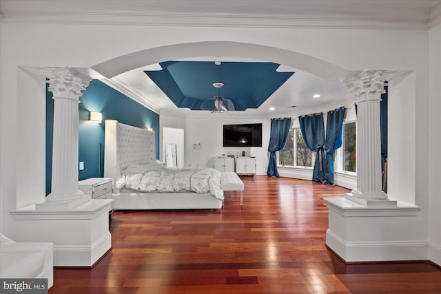 bedroom with arched walkways, a raised ceiling, and decorative columns