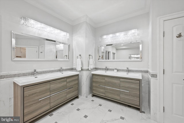 full bathroom with double vanity, a wainscoted wall, marble finish floor, crown molding, and tile walls