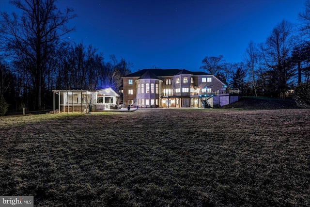 back of house at twilight with a lawn