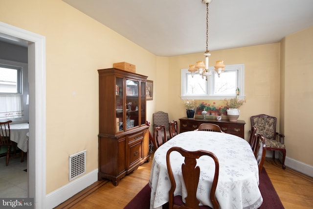 dining space with a healthy amount of sunlight, an inviting chandelier, and light hardwood / wood-style flooring