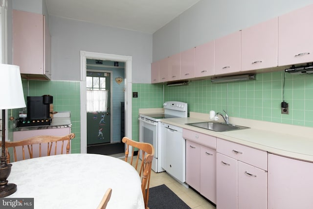 kitchen with sink, white appliances, white cabinetry, tile walls, and light tile patterned flooring