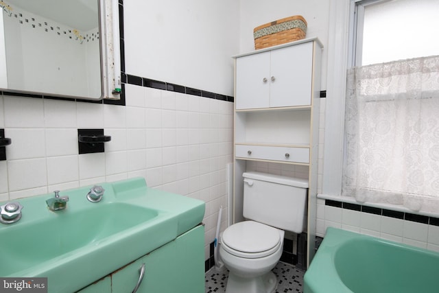 bathroom with vanity, a bathing tub, tile walls, and toilet