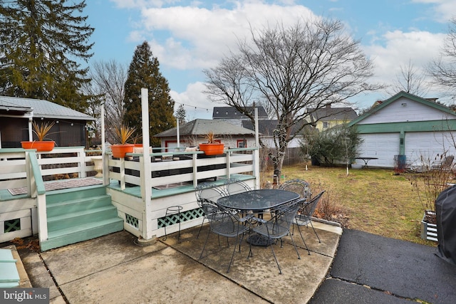 view of patio / terrace featuring a garage, a wooden deck, and an outbuilding