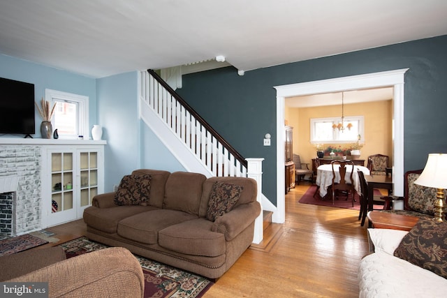 living room featuring a fireplace, light hardwood / wood-style floors, and a notable chandelier