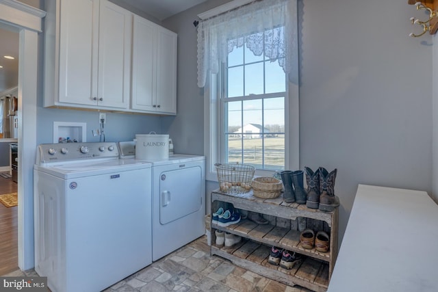 clothes washing area with cabinets, washer and clothes dryer, and a wealth of natural light